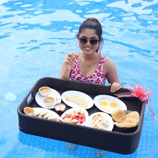 a woman posing in the swimming pool with a floating breakfast tray with many items inside - Shanti Seaview Resort & Spa