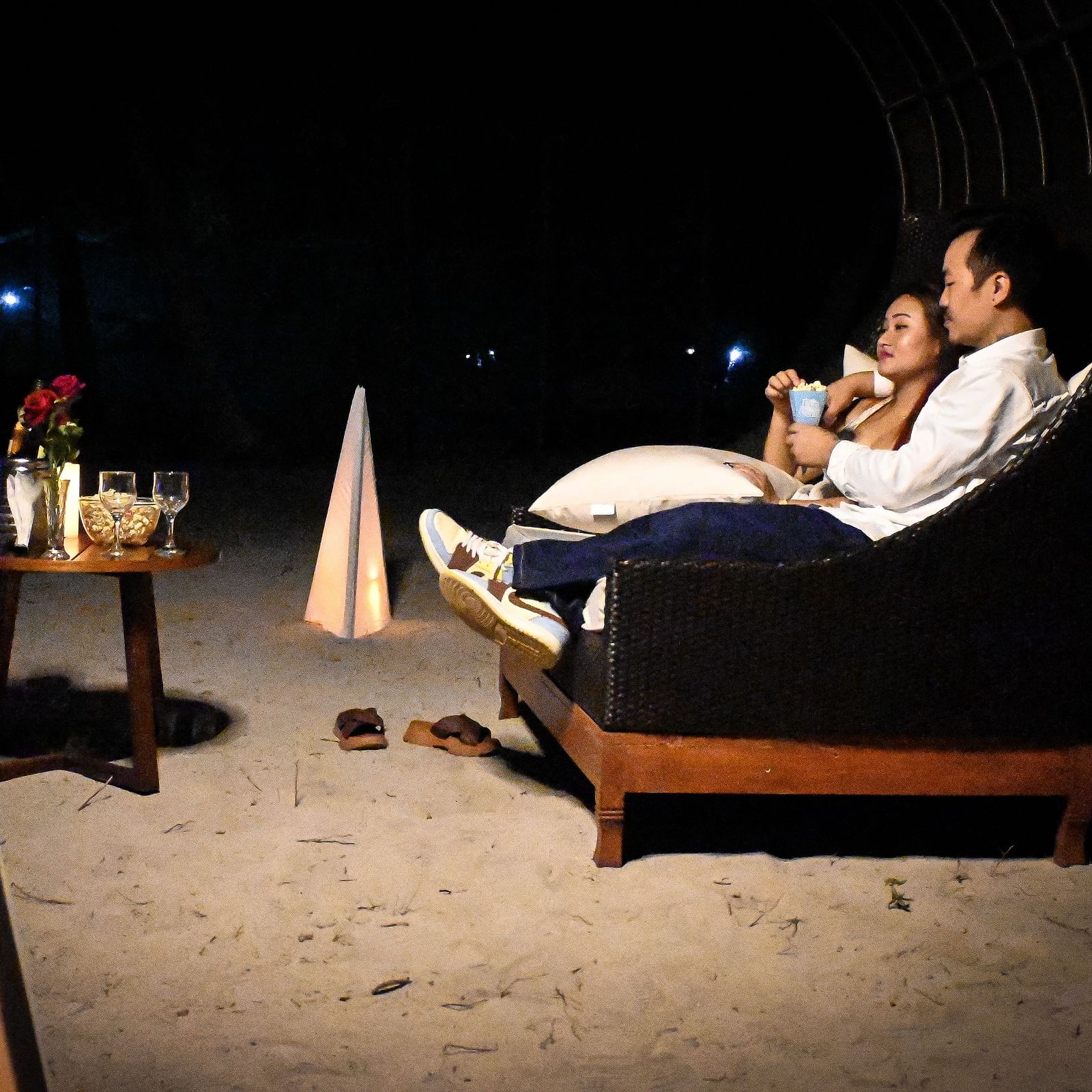 A couple sharing popcorn sitting in a couch setting with wine and roses in front of them - Coral Reef Resort & Spa, Havelock