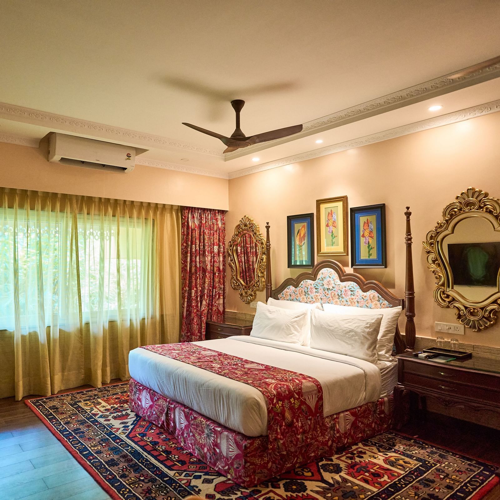 A spacious room featuring a large bed, wooden bedside tables, and windows draped with curtains at Mayfair Manor, Alibag