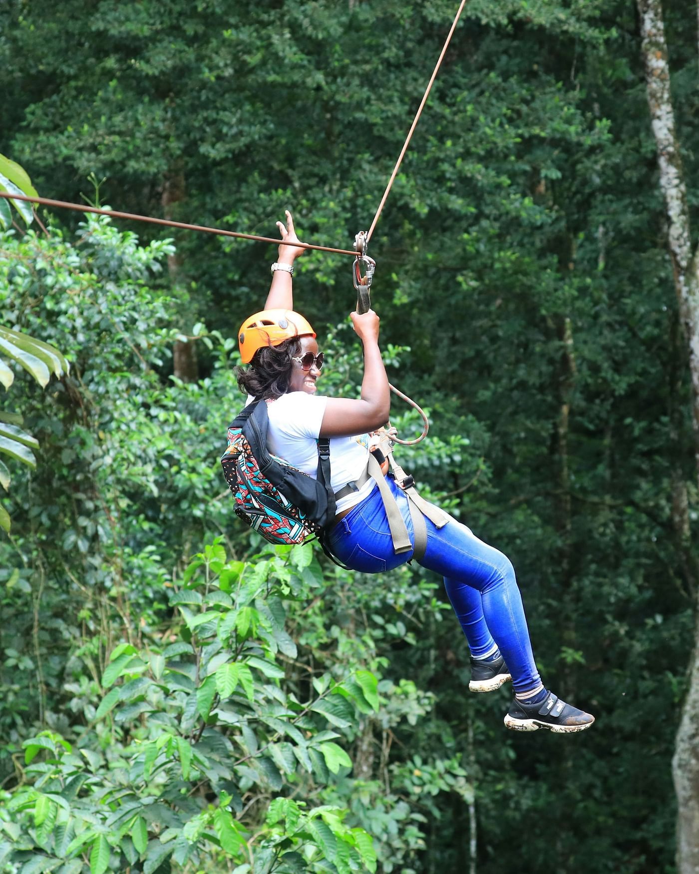 Image of a woman enjoying zip lining with a background of lush trees 