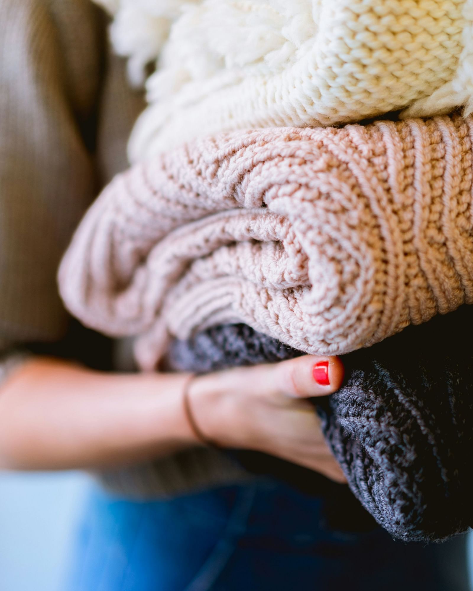 Person holding a stack of folded warm blankets or towels