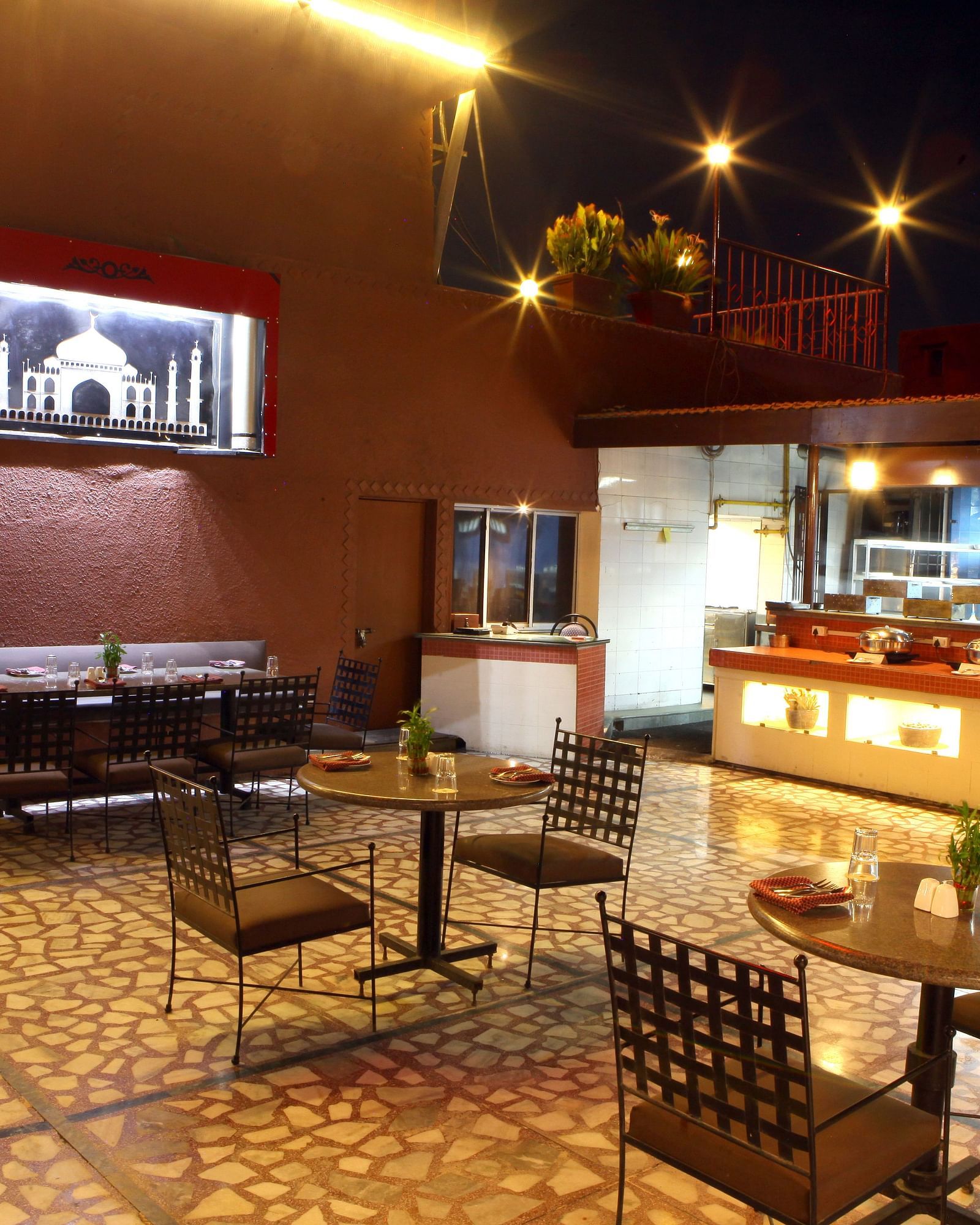 A warmly lit dining or lounge area with tables and chairs at Lords Plaza Surat.