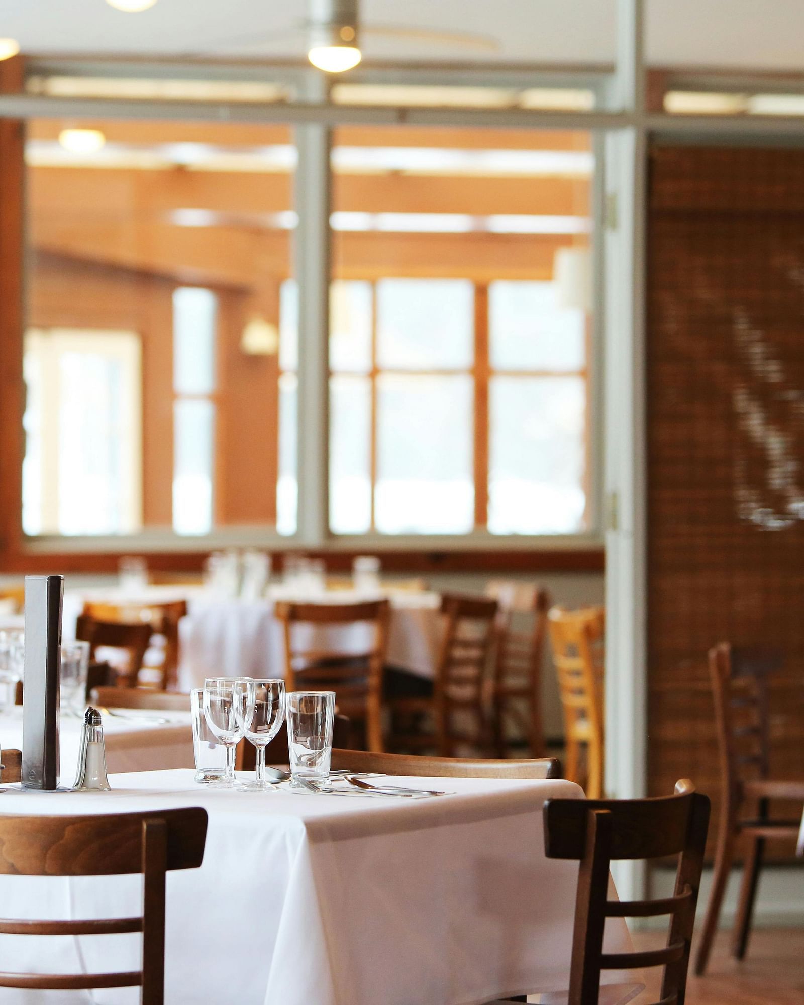 A softly blurred view of a restaurant dining area with set tables and chairs awaits patrons.