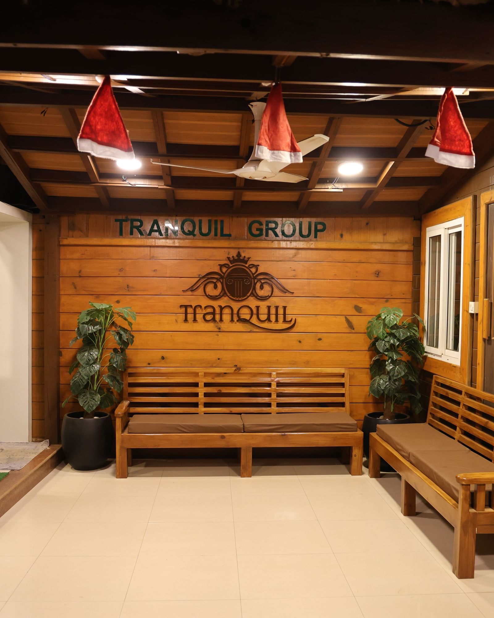 Interior view of a rustic, wood-panelled reception or common area with benches, warm lighting, and traditional decor - Tranquil Beach Resort, Harihareshwar