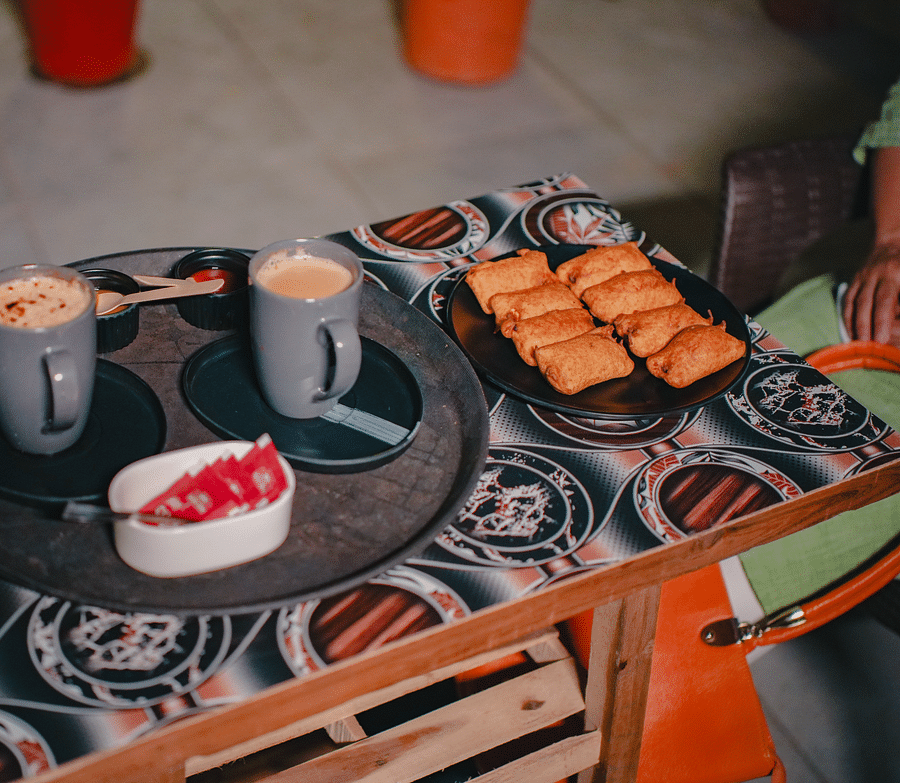 An image of a tea table where a tray is placed which has two cups of hot beverages, sauces, sugar sachets, and fritters - Rangamati Garden Resort