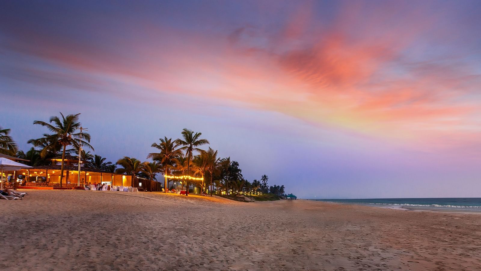 view of building in the background with trees and the evening sky as well - caravela Beach Resort Goa 