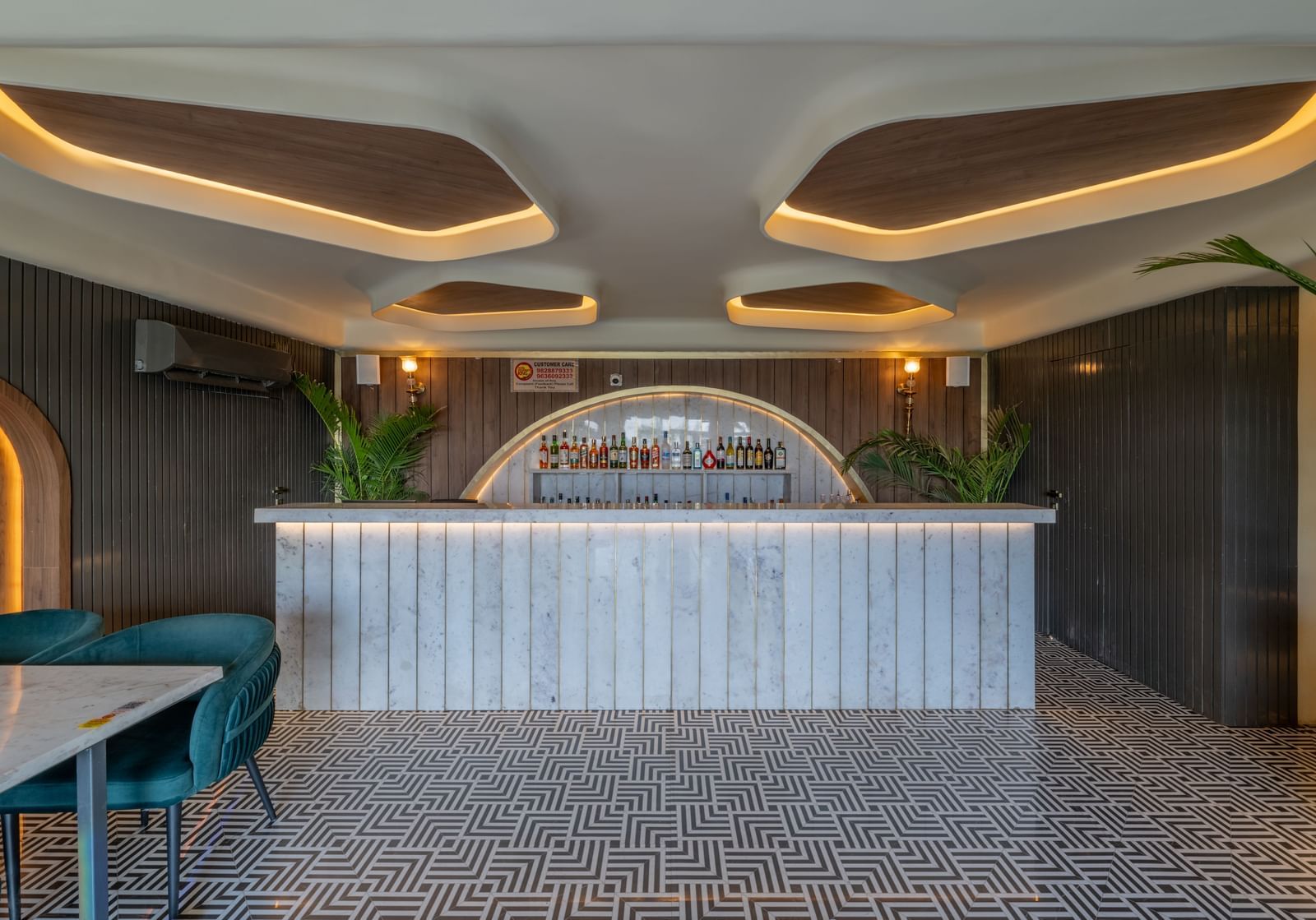A bar reception with white panelling and drinks arranged in a curve counter under warm ceiling lights at Hotel Highway King, Jaipur.