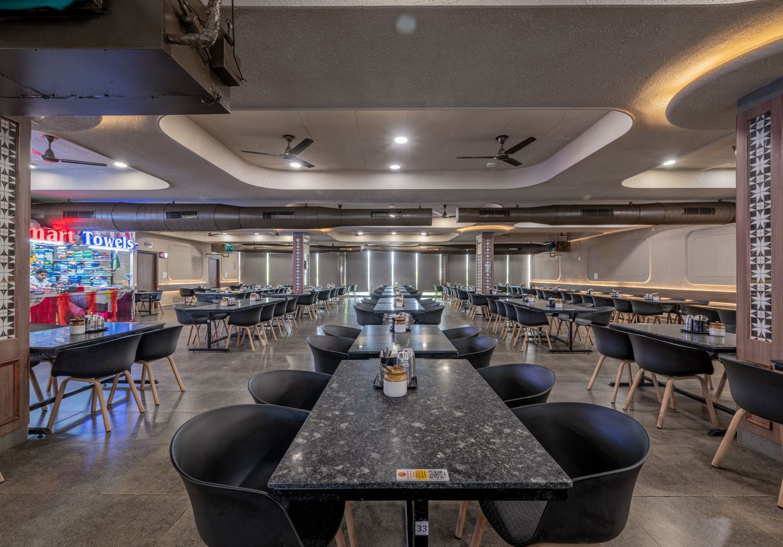 A close-up view of a table with chairs arranged neatly around it, with warm lighting, at Hotel Highway King, Neelka.