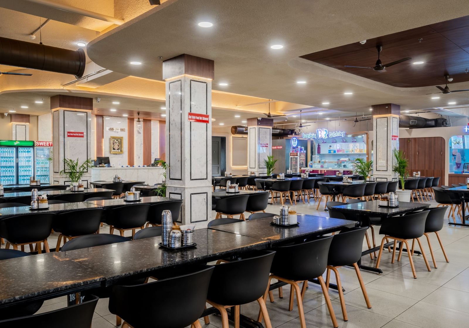 Modern restaurant with neatly arranged seating and elegant ceiling lights at Hotel Highway King, Neemrana.