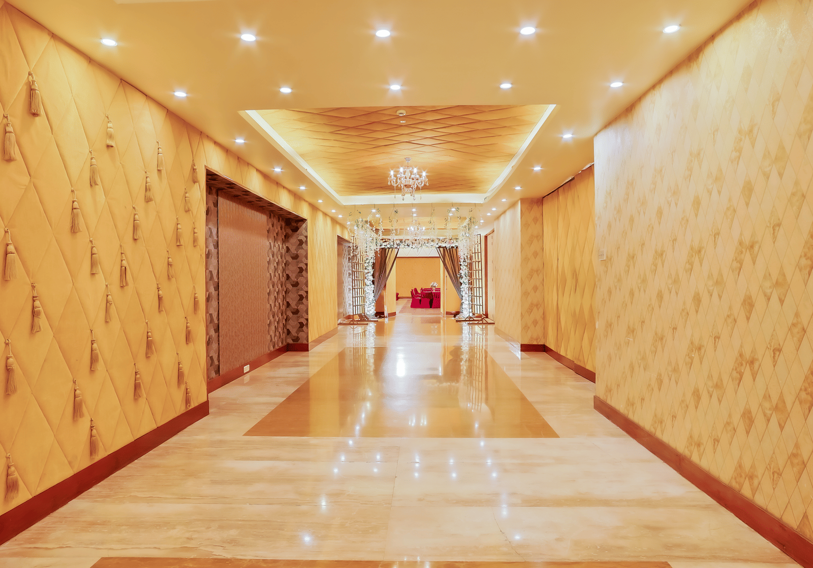 A brightly lit, long hotel corridor with patterned wallpaper and polished floors at The Conway, Meerut.