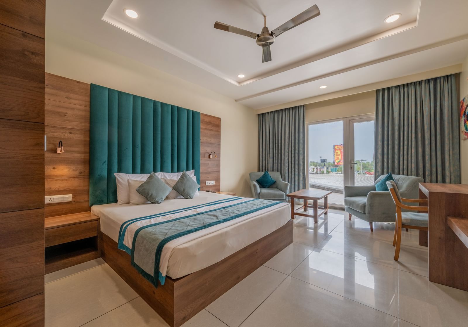 Elegant room with king size bed, full-length curtains, and work station with a seating area nearby at Hotel Highway King, Bilaspur.