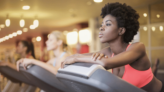 Women exercising on treadmills in a brightly lit, modern fitness centre.