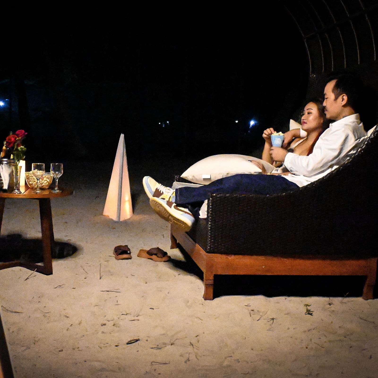 A couple sharing popcorn sitting in a couch setting with wine and roses in front of them - Coral Reef Resort & Spa, Havelock