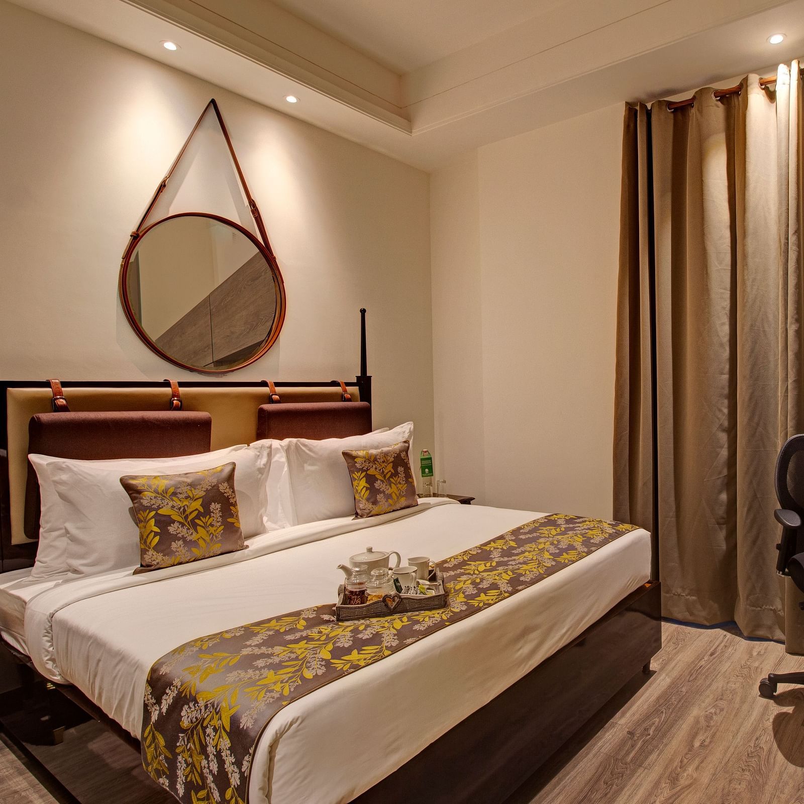 a king bed with side tables and adesk opposite the bed inside Executive Suite at Rhythm Gurugram