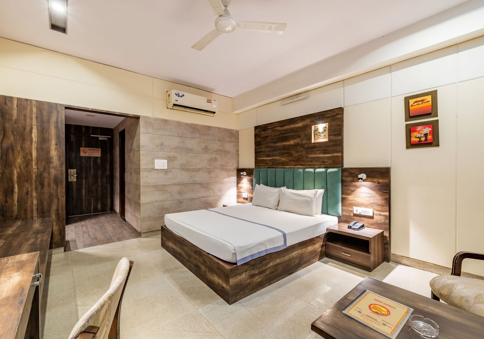Extended view of the Maharaja Deluxe Room at Hotel Highway King, Behror, furnished with a double bed, air-conditioning, a work desk and seating area for two.
