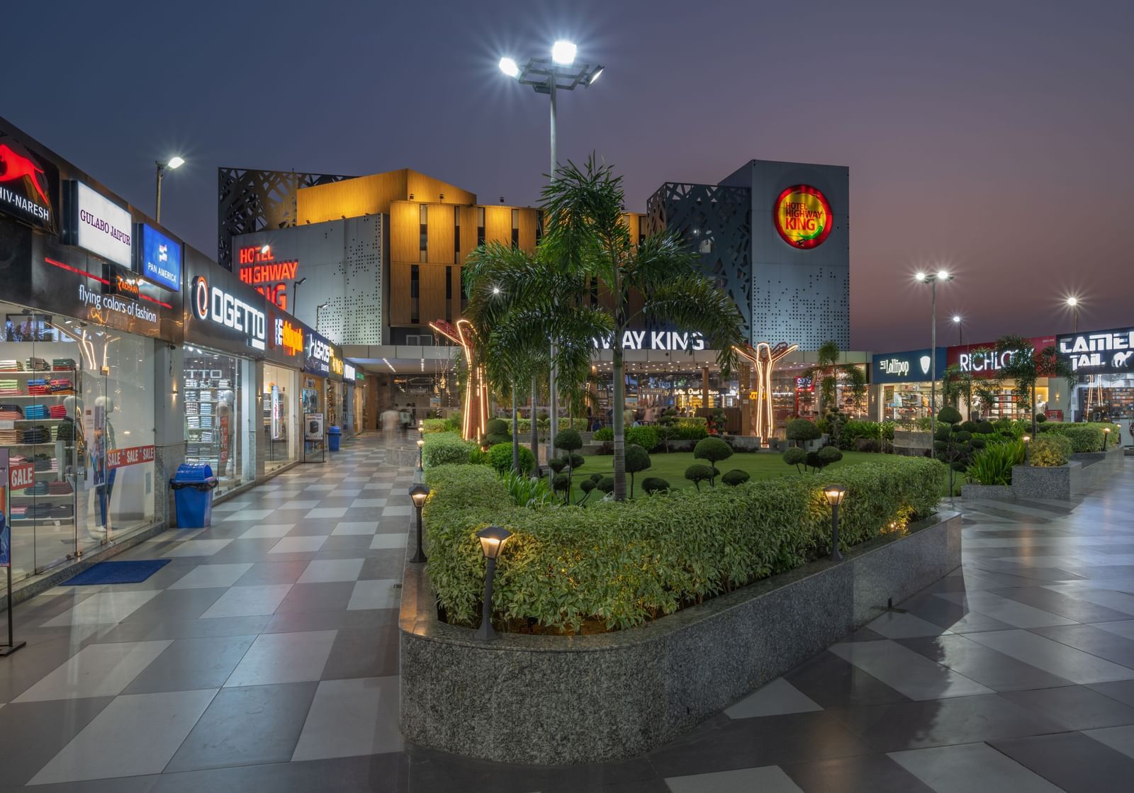 Retail and garden area near the hotel entrance with evening lights at Hotel Highway King, Bilaspur.