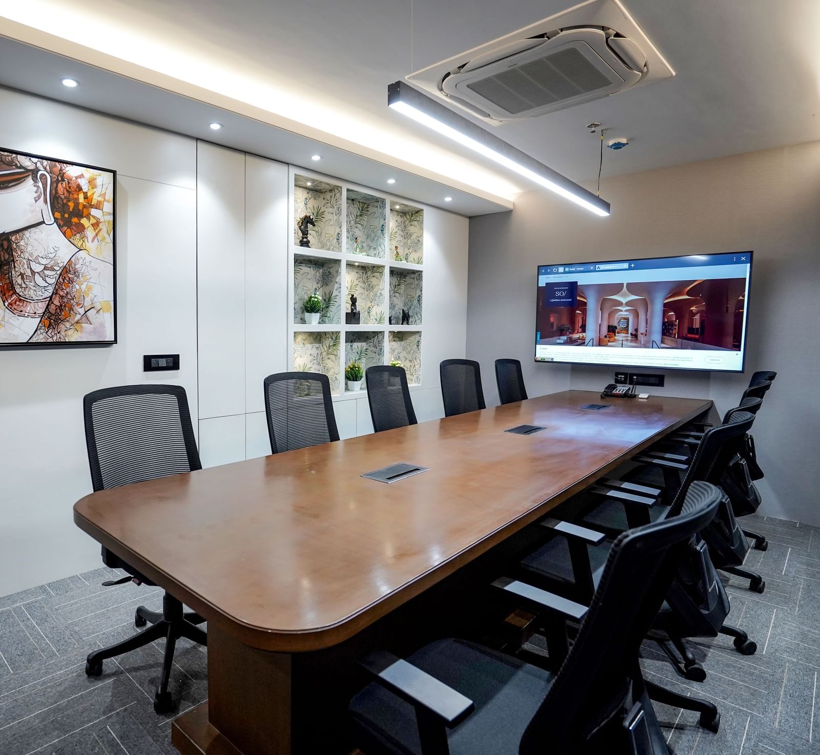 The boardroom at M2 Square by Monday Premium featuring a long wooden table along with an abstract painting hung on the wall.