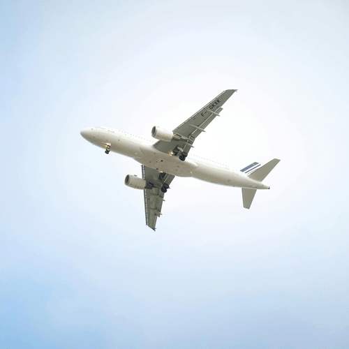 A view from below of a plane flying above with blue sky in the background.