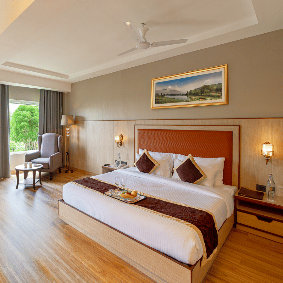 Elegant room at The Lalita Grand Mathura - Vrindavan with a king size bed, wooden flooring, large window views, and refined contemporary decor.