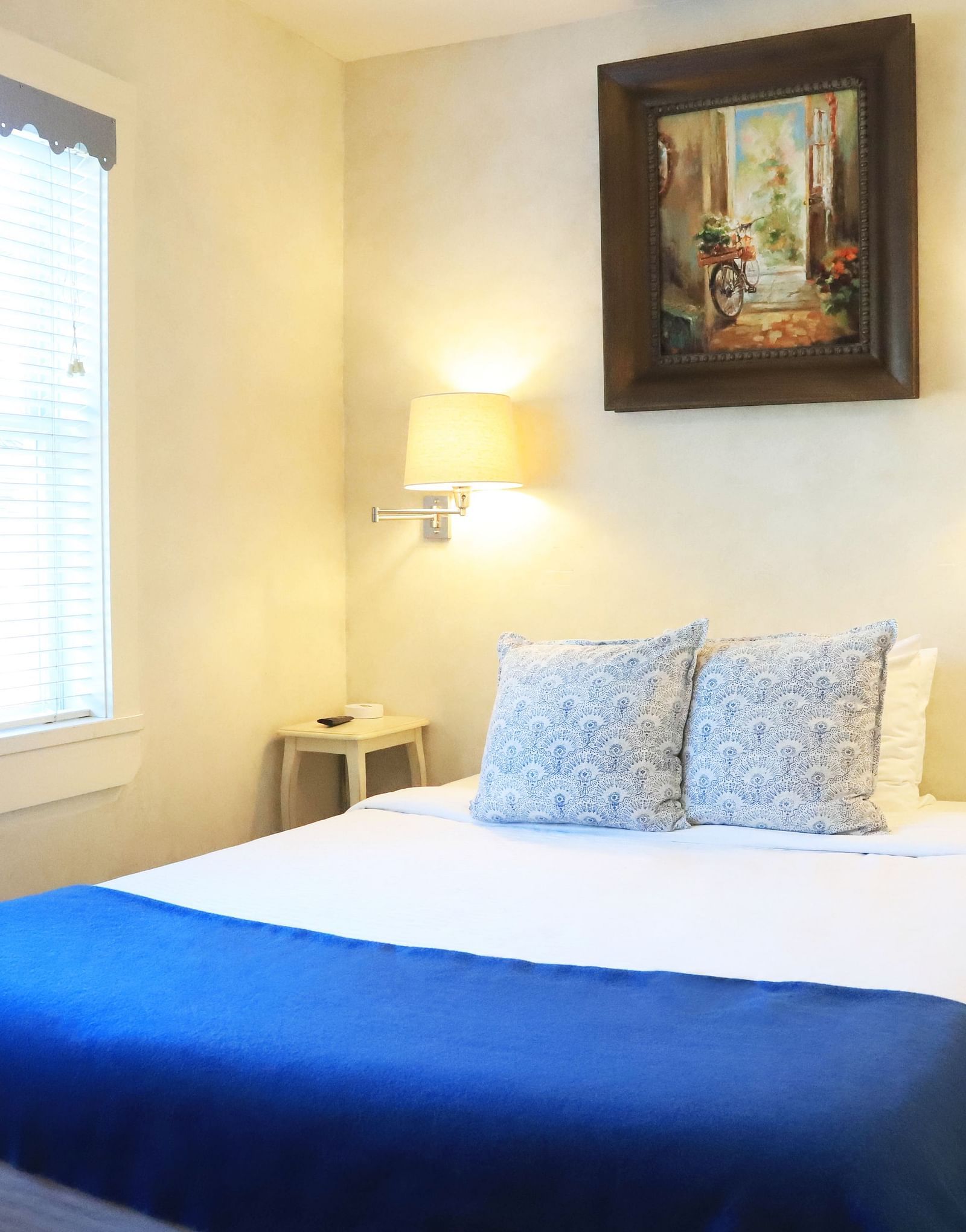 Bedroom with a blue throw, white bedding, and framed art at Hartstone Inn.