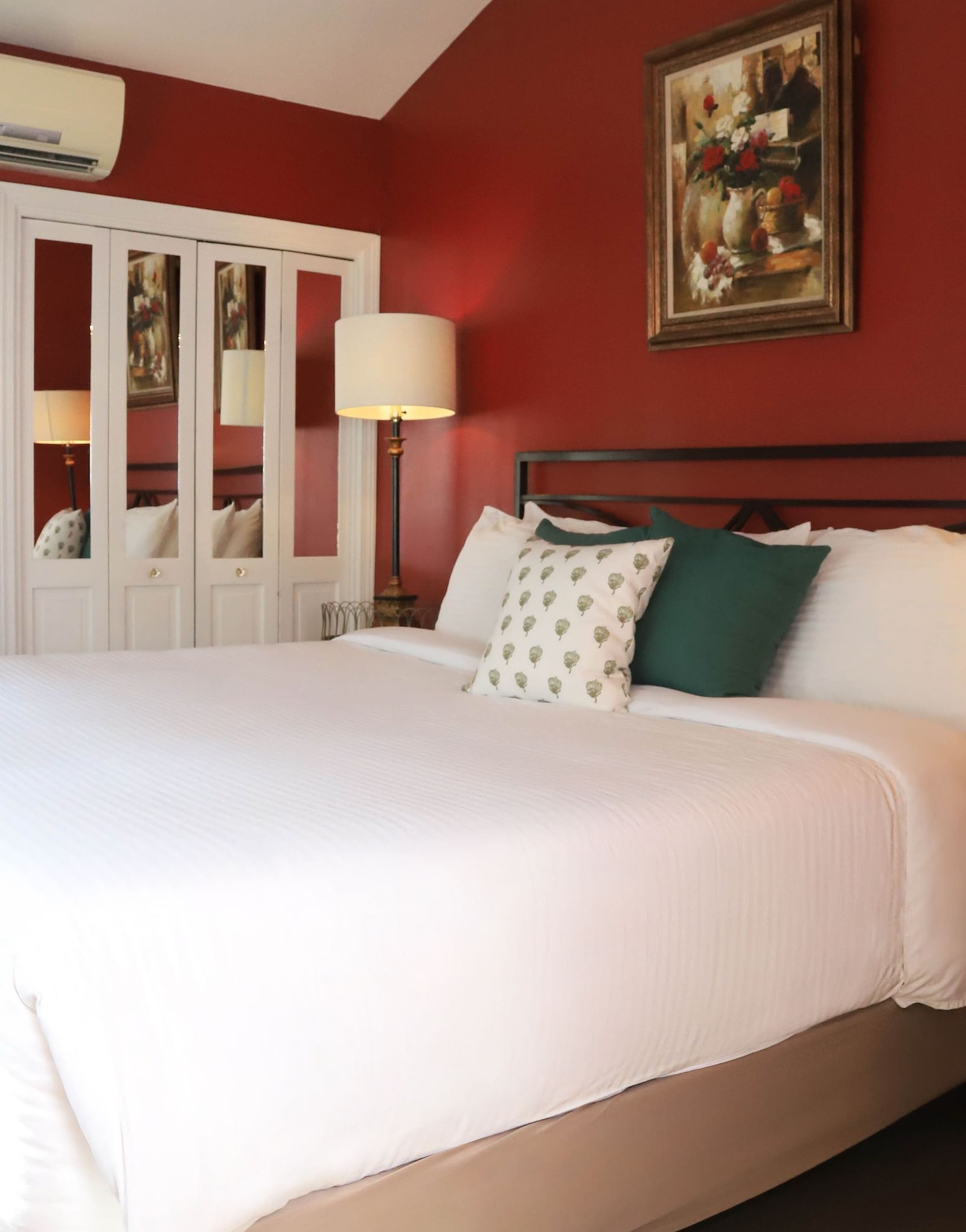 Hotel room with red walls, bed, and a lamp beside the bed at Hartstone Inn.