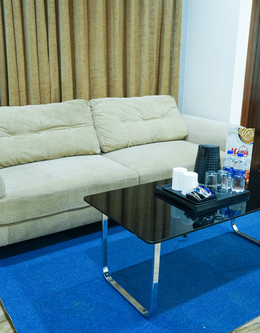 Cream sofa and black glass coffee table on a blue rug in the King Room with Balcony at Lime Tree Hotel Near 32nd Avenue