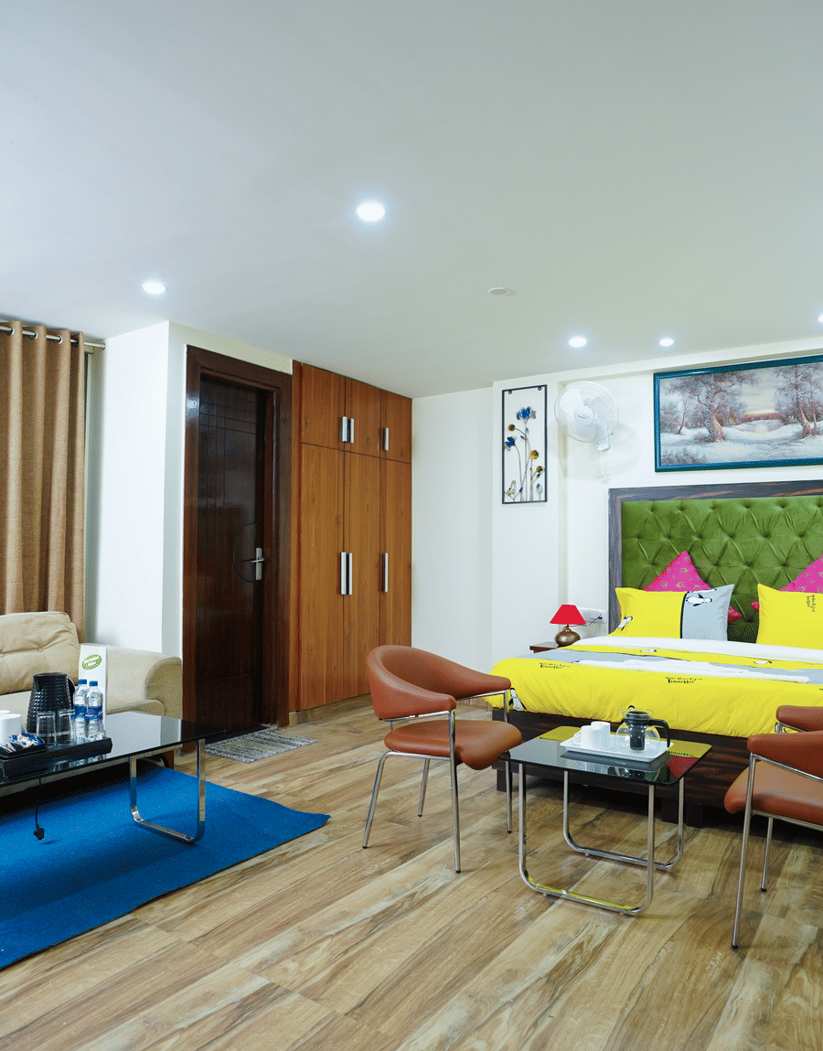 King Room with Balcony with a green headboard, yellow bedding, a sofa and a blue rug at Lime Tree Hotel Near 32nd Avenue