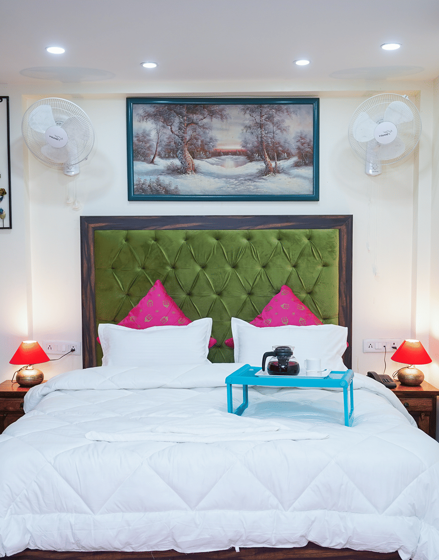 King bed with a green tufted headboard, white duvet and laptop tray in the Superior King Room, Lime Tree 32nd Avenue