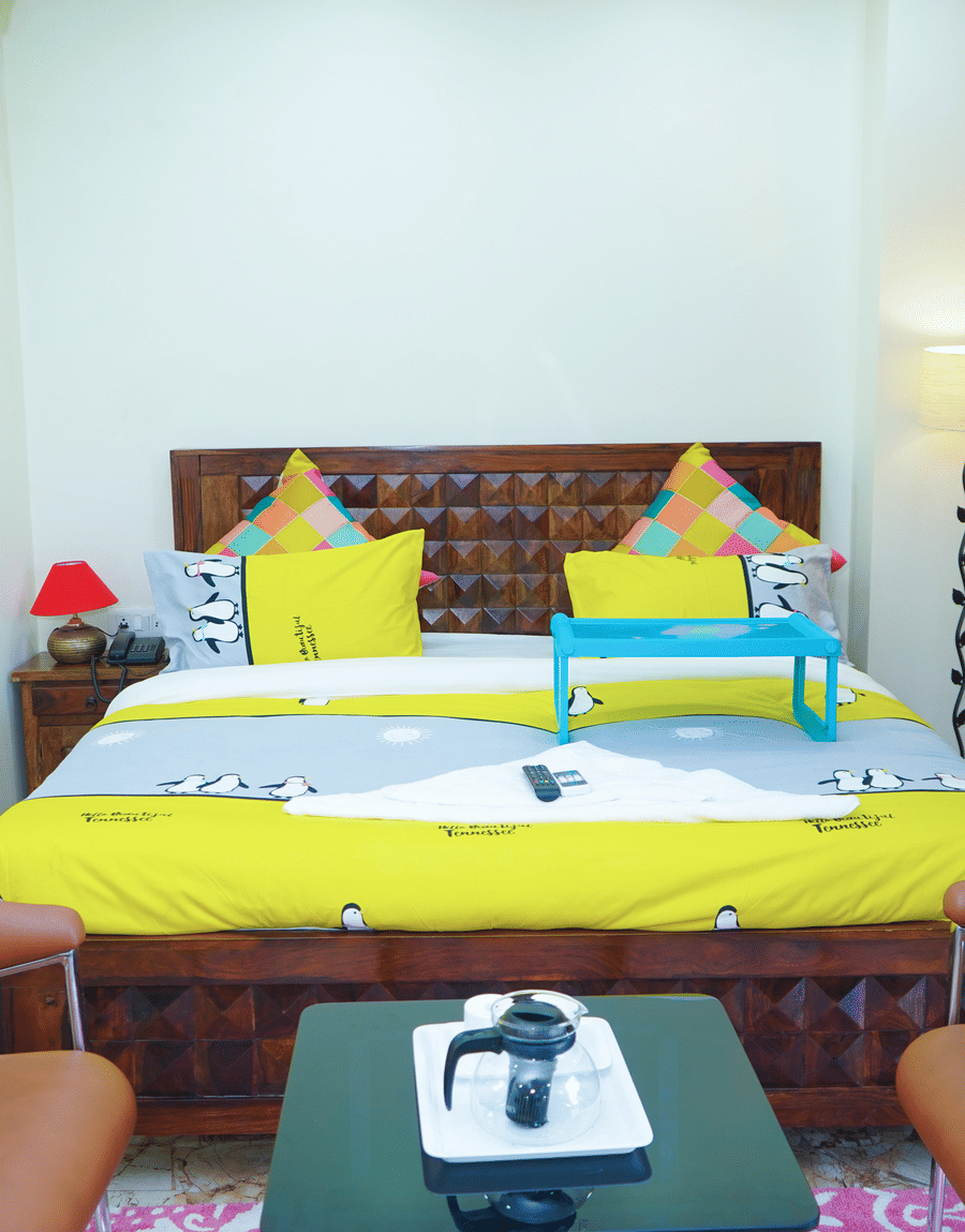 Wooden bed with yellow bedding and a breakfast tray in the Superior King Room at Lime Tree Hotel Near 32nd Avenue