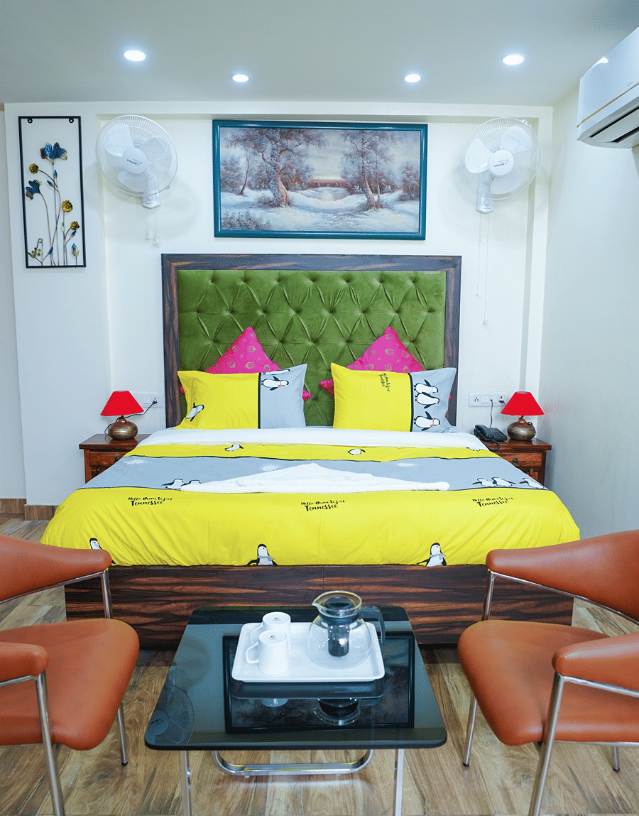 King bed with a green tufted headboard and red lamps in the King Room with Balcony at Lime Tree Hotel Near 32nd Avenue