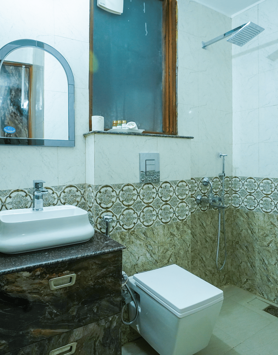 Bathroom with a washbasin, an arched mirror and a wall-hung toilet in the King Room at Lime Tree Hotel Near 32nd Avenue