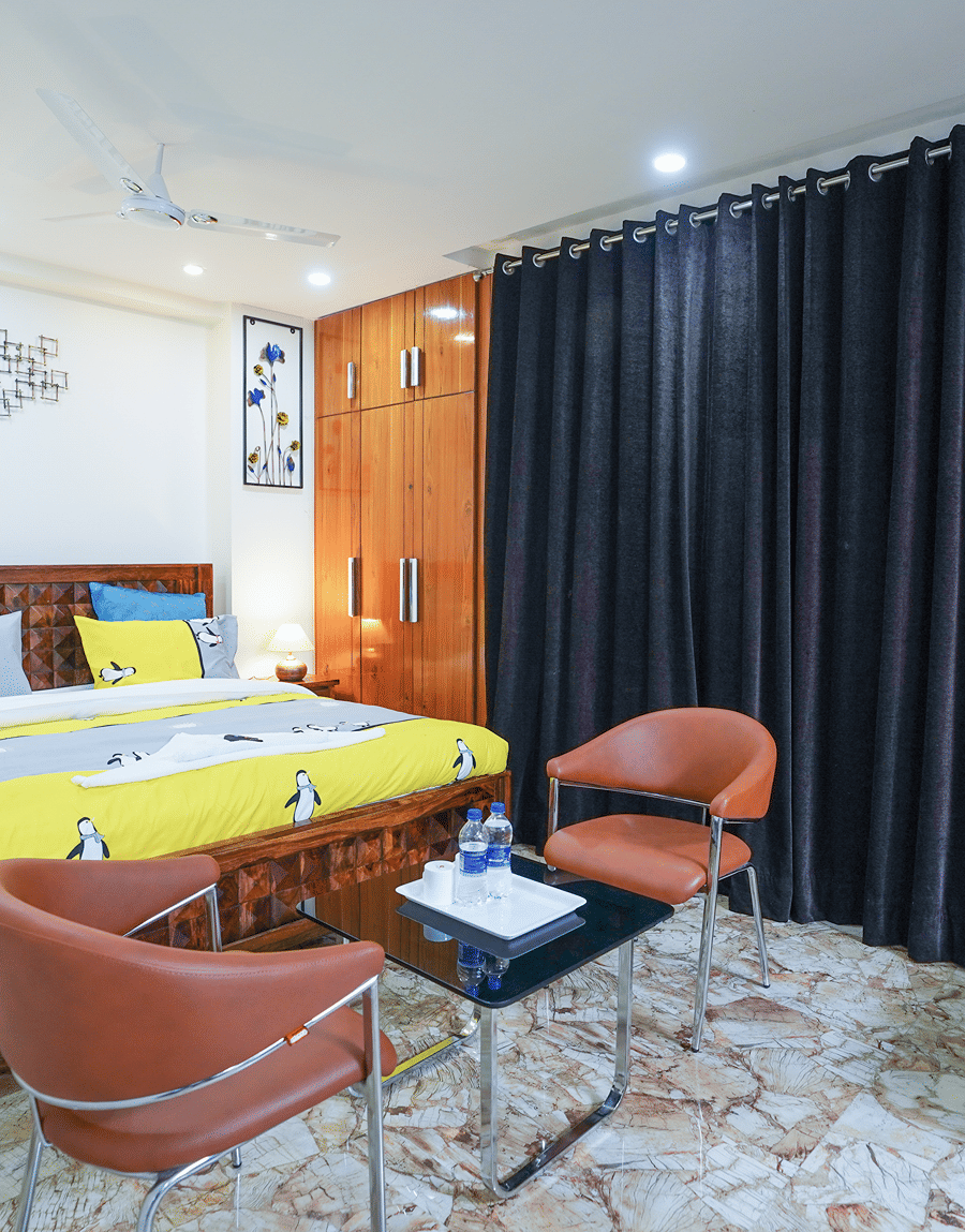 King bed, wardrobe and tan leather chairs round a glass table in the King Room with Balcony, Lime Tree Hotel Near 32nd Avenue