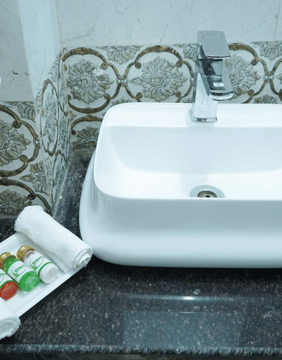 White vessel washbasin with toiletries on a granite counter in the King Room bathroom, Lime Tree Hotel Near 32nd Avenue