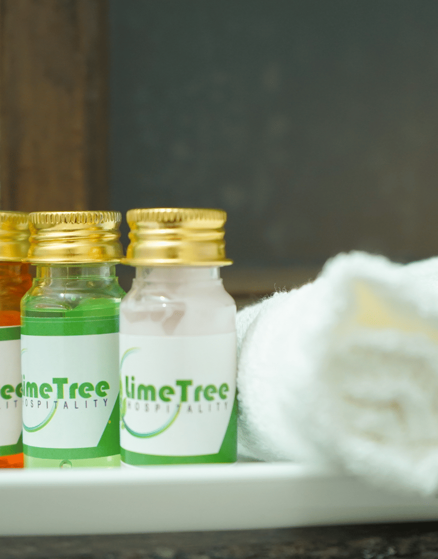 Lime Tree branded toiletry bottles beside a rolled towel in the King Room bathroom at Lime Tree Hotel Near 32nd Avenue