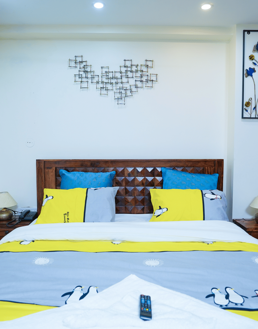 King bed with blue and yellow cushions below heart-shaped wall art in the Superior King Room, Lime Tree 32nd Avenue