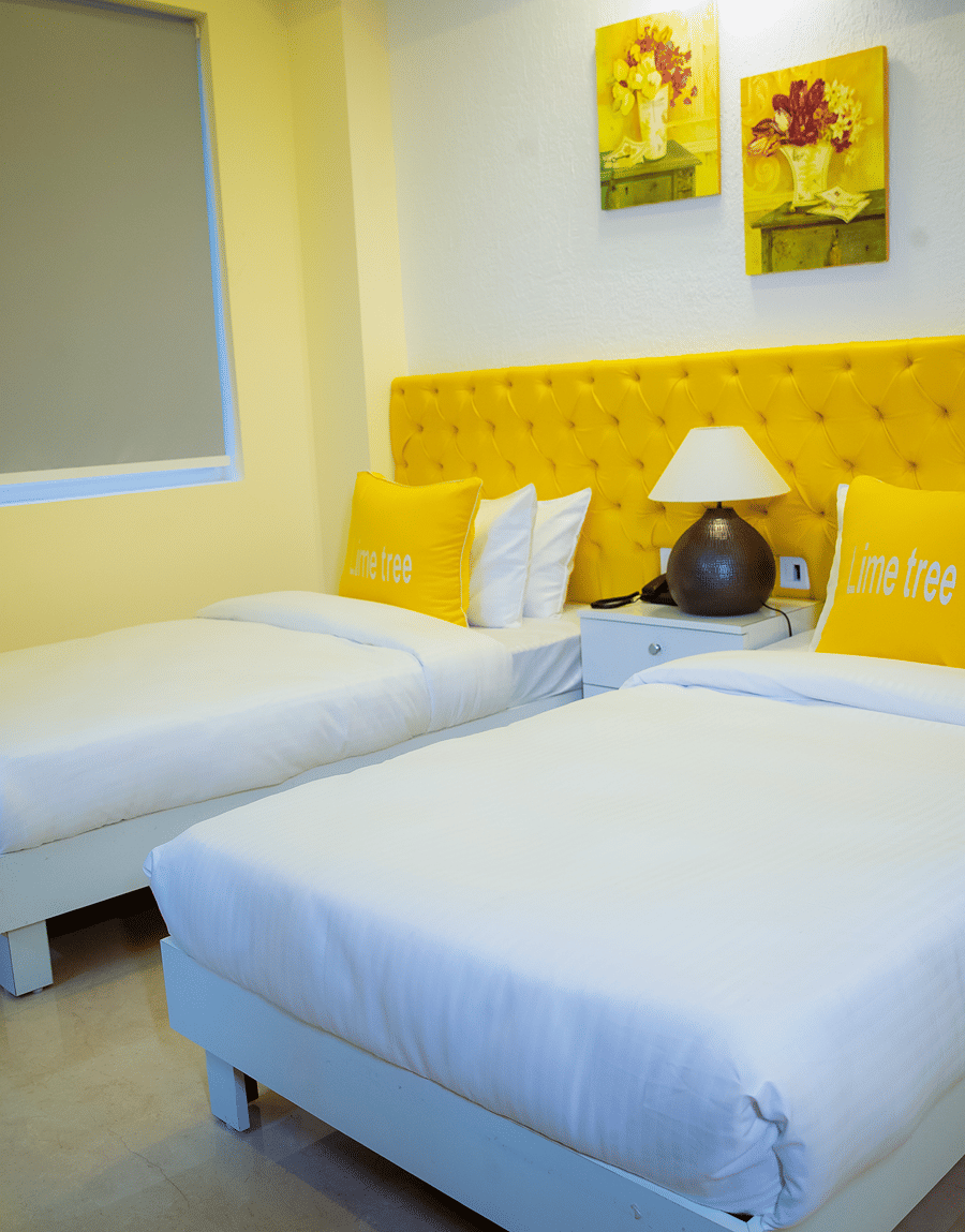 Twin beds with a yellow tufted headboard and sunflower art in the Standard Studio with Balcony, Lime Tree Luxury Studio