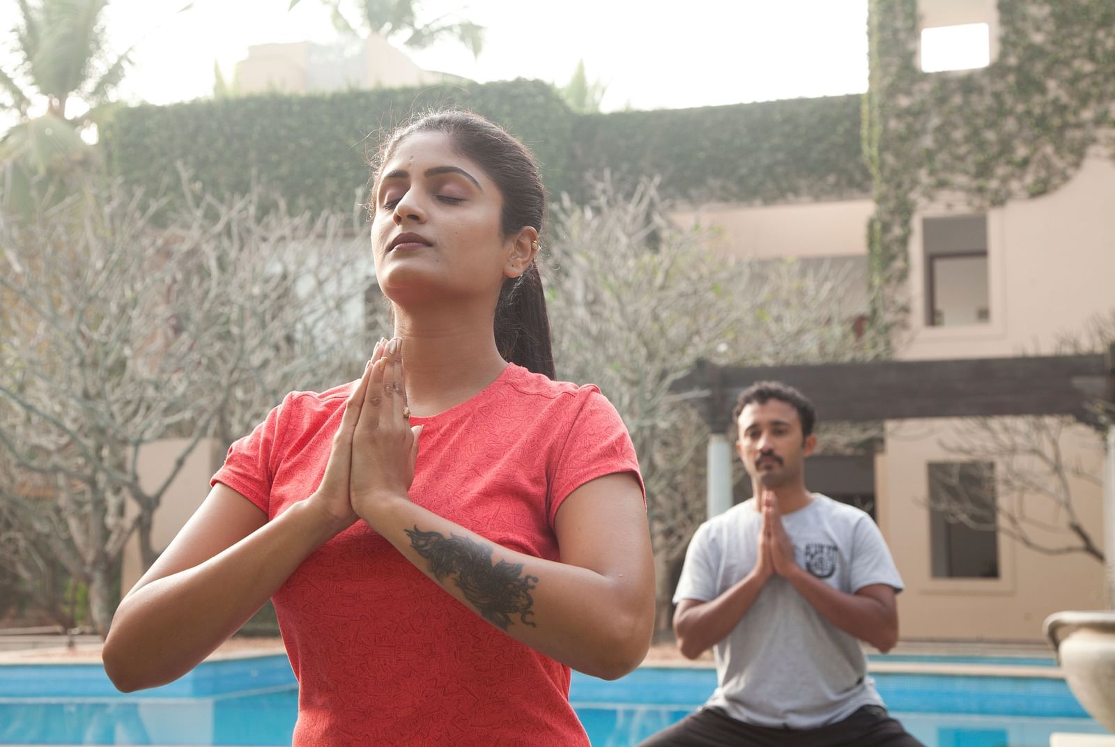 People doing yoga poses outdoors, sunlight, trees in background - Shreyas Retreat