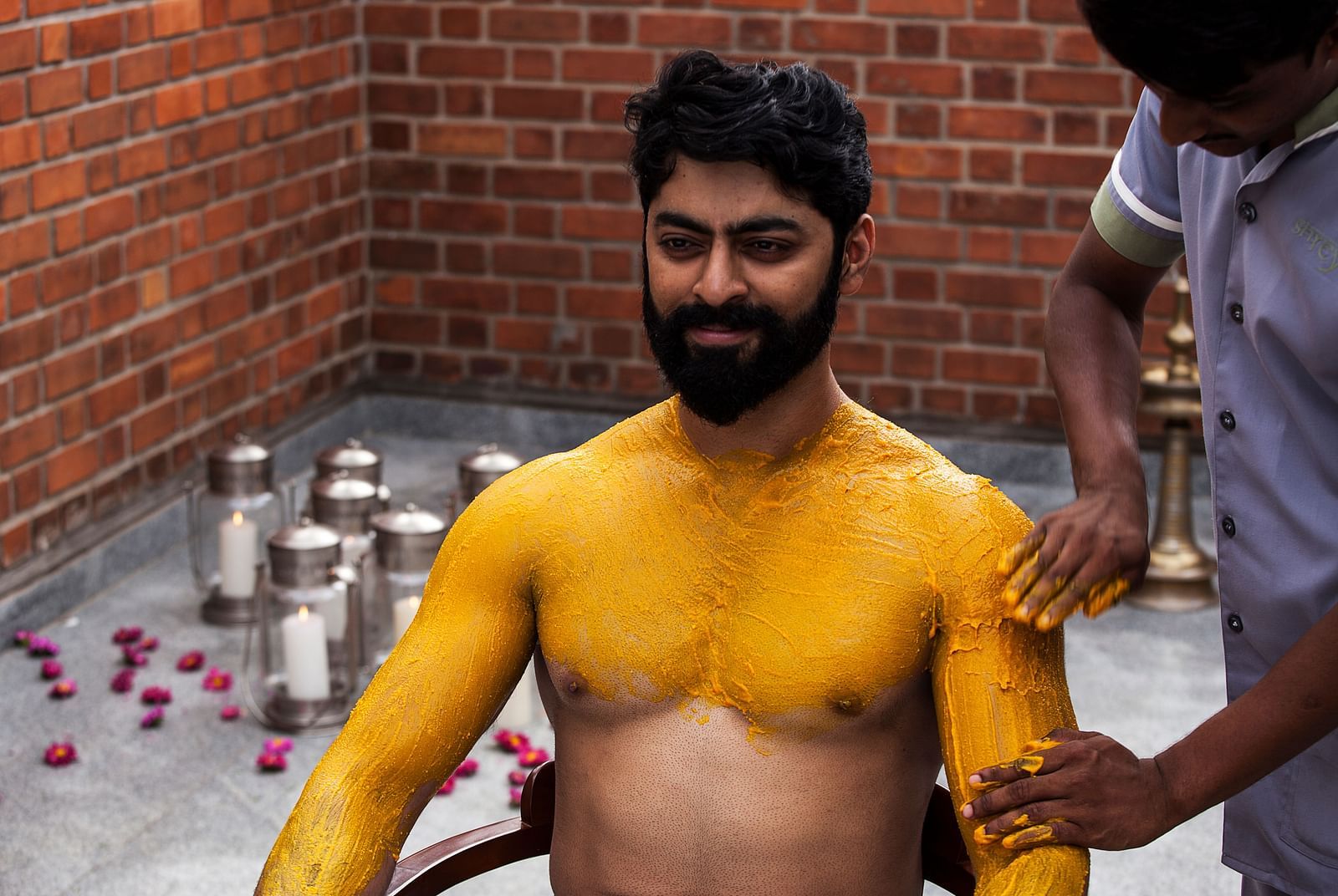 A person with yellow markings on their body, brick wall background - Shreyas Retreat