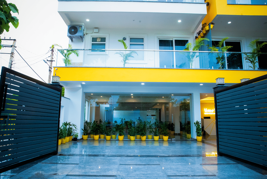 Entrance gate and driveway lined with potted plants at Lime Tree Luxury Studio, Gurgaon