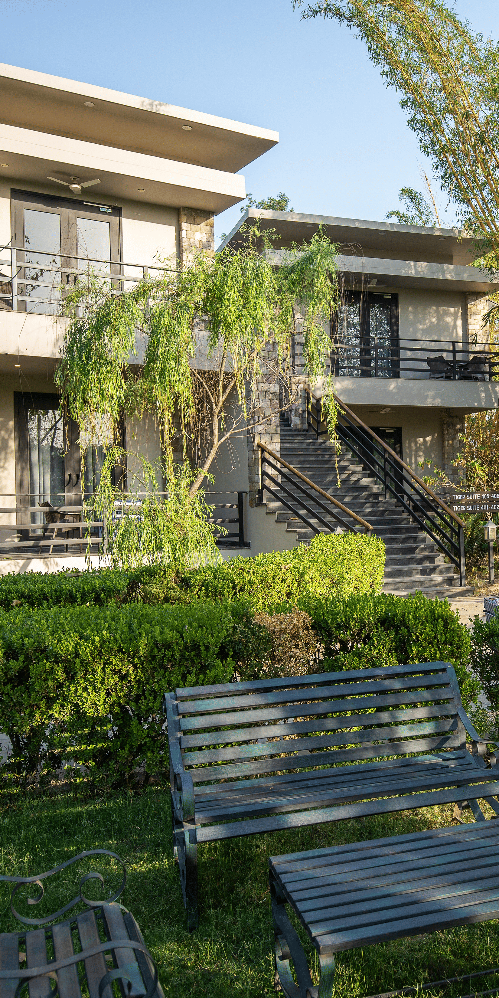 Lawn area of the resort building with a lush green garden and outdoor seating in the daytime at The Golden Tusk, Jim Corbett