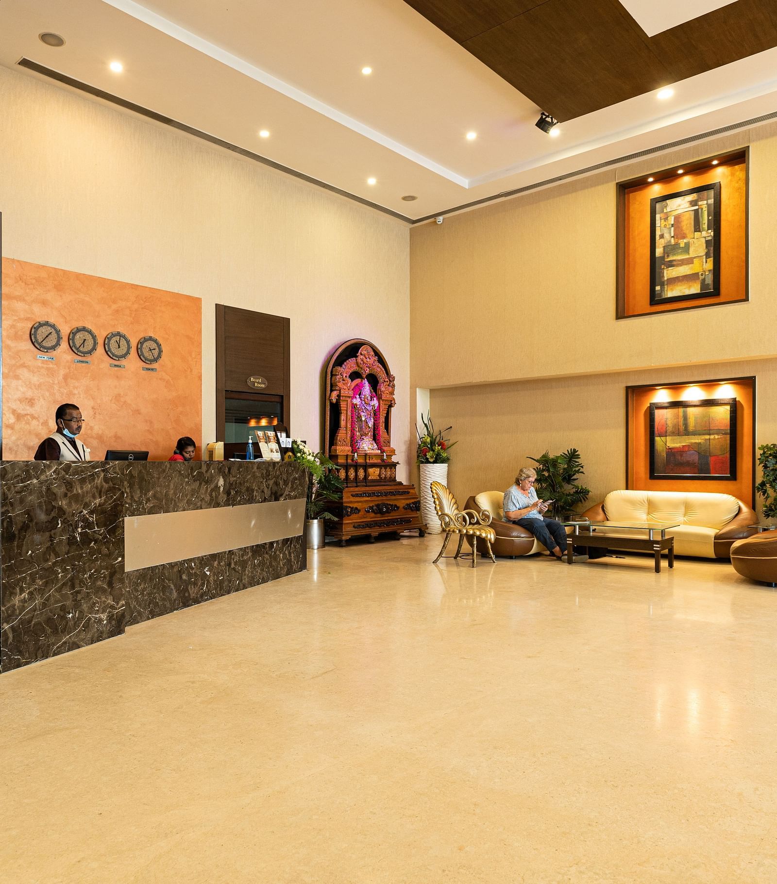 A reception area with people sitting behind the desk - Hotel Pai Vista, Mysore - Mysore Hotel Contact Number