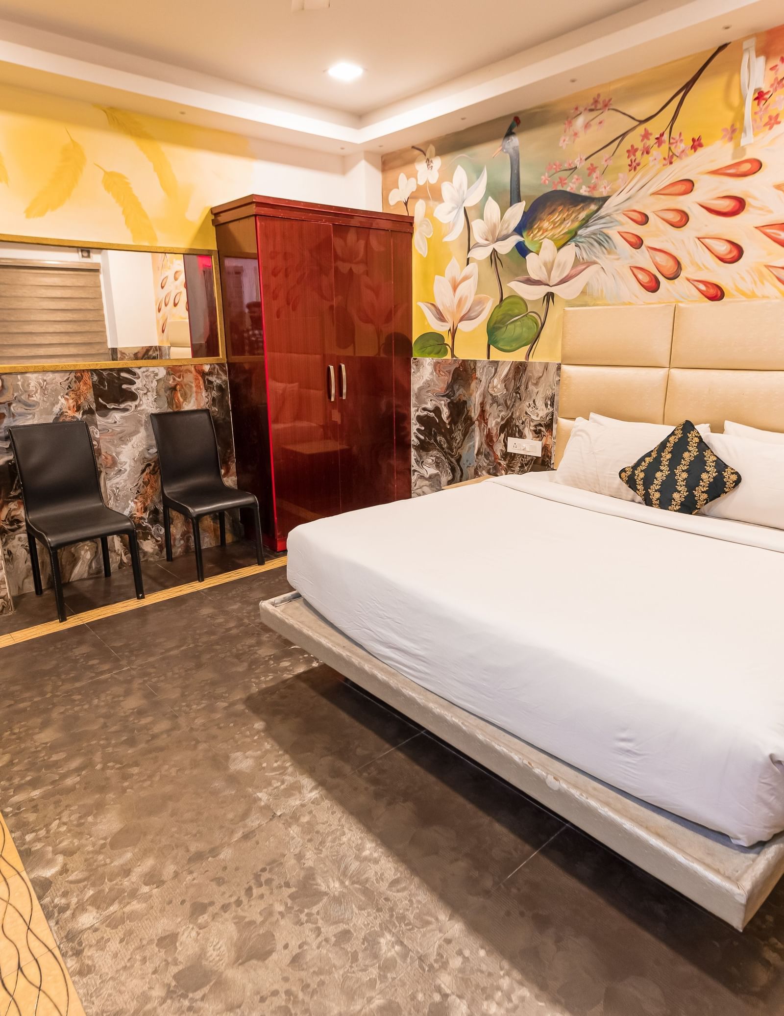 A double bed, chairs and a cupboard at the Deluxe Non AC Room at Parakkat Nature Hotel and Resorts Munnar