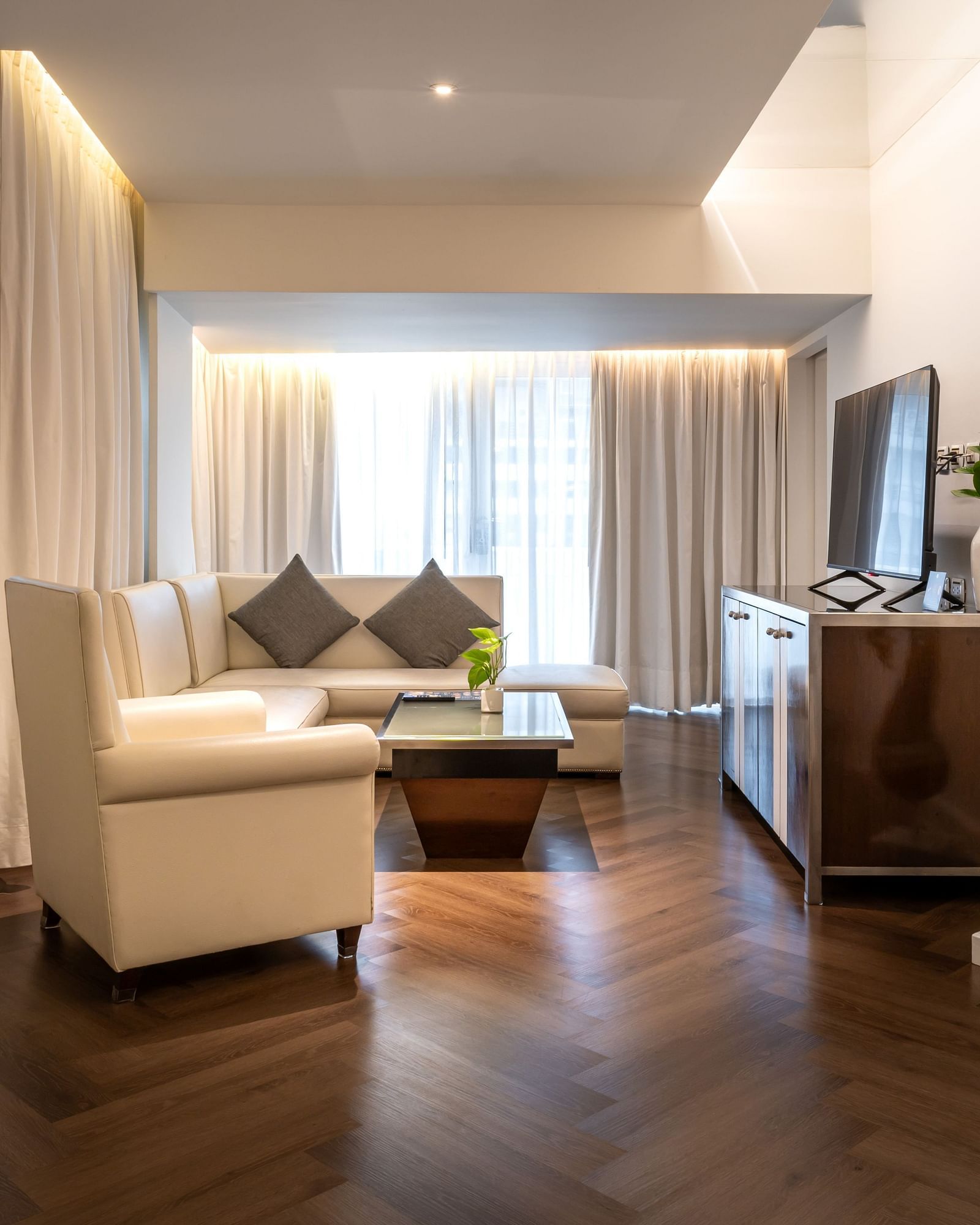 A modern living room featuring designer sofas and a TV atop a wooden table - Night Hotel Bangkok