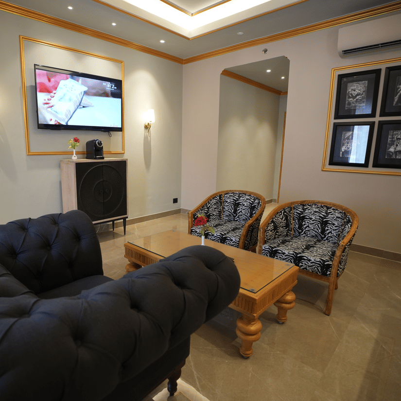 An Executive Suite living room at Clarks Khajuraho with sofas, a center table, a wall-mounted television, and framed artwork.