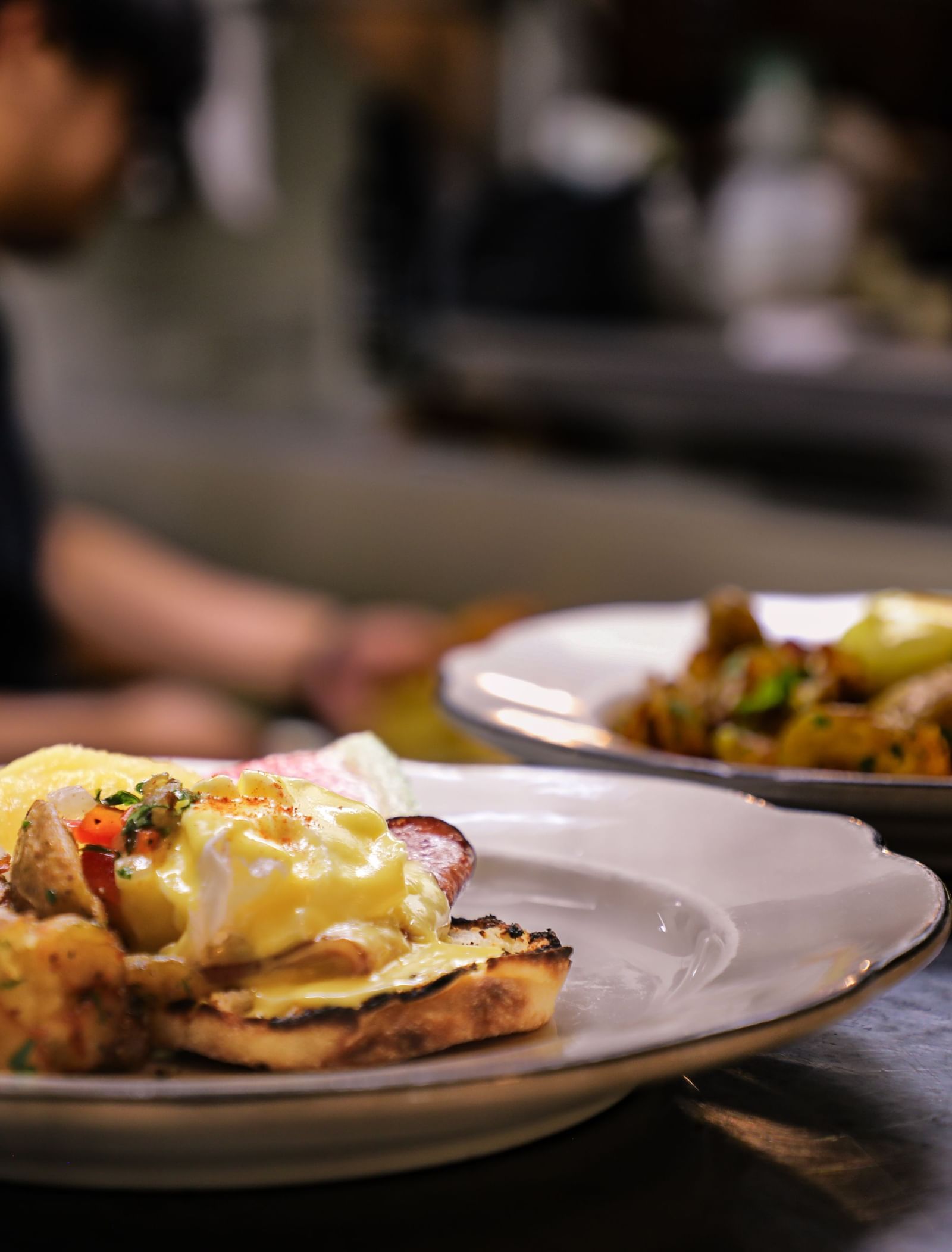 Freshly prepared gourmet dishes sit on a counter with a chef in the background at the Tallman Hotel.