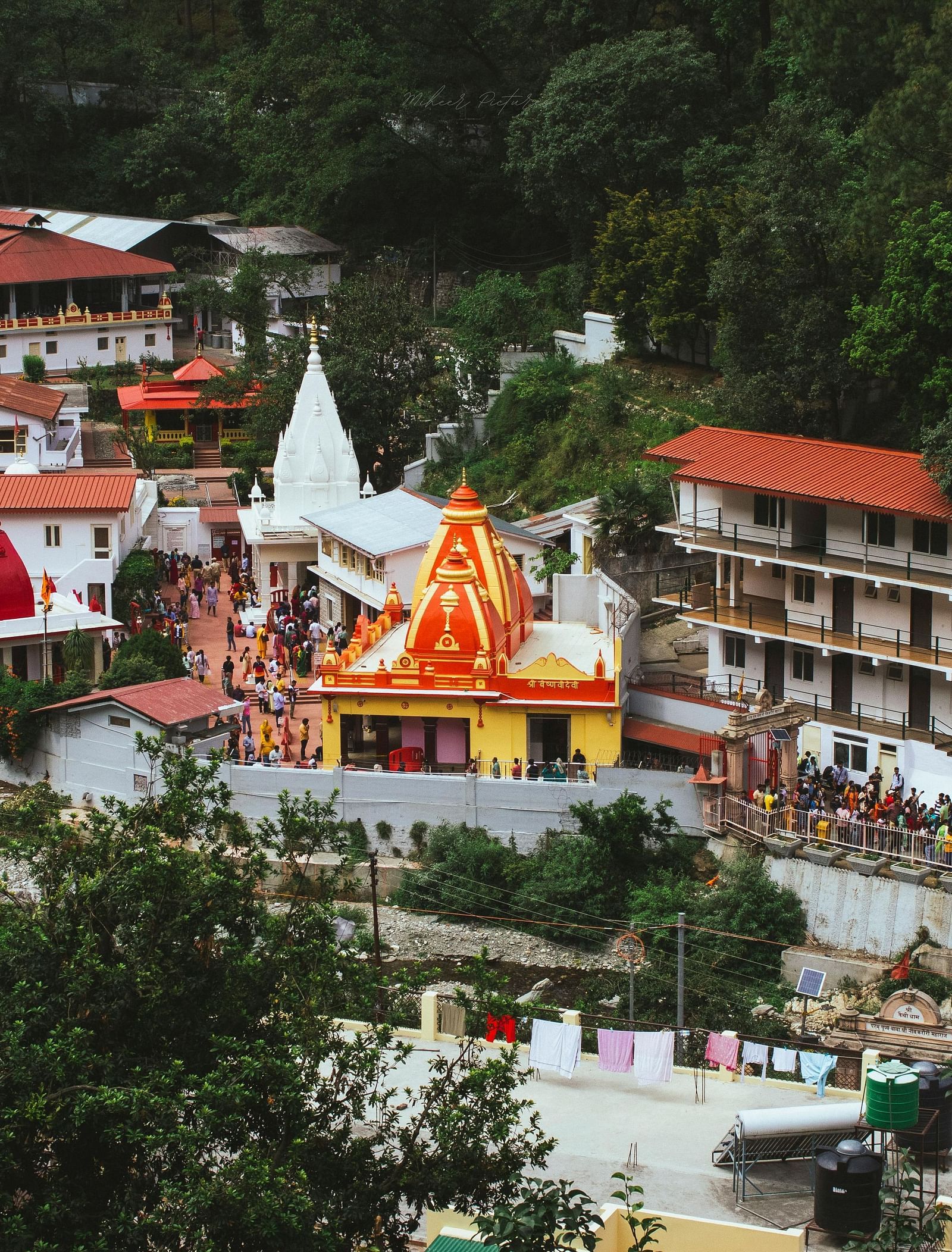 image featuring a bright yellow and red coloured temple in Nainital amidst various other buildings