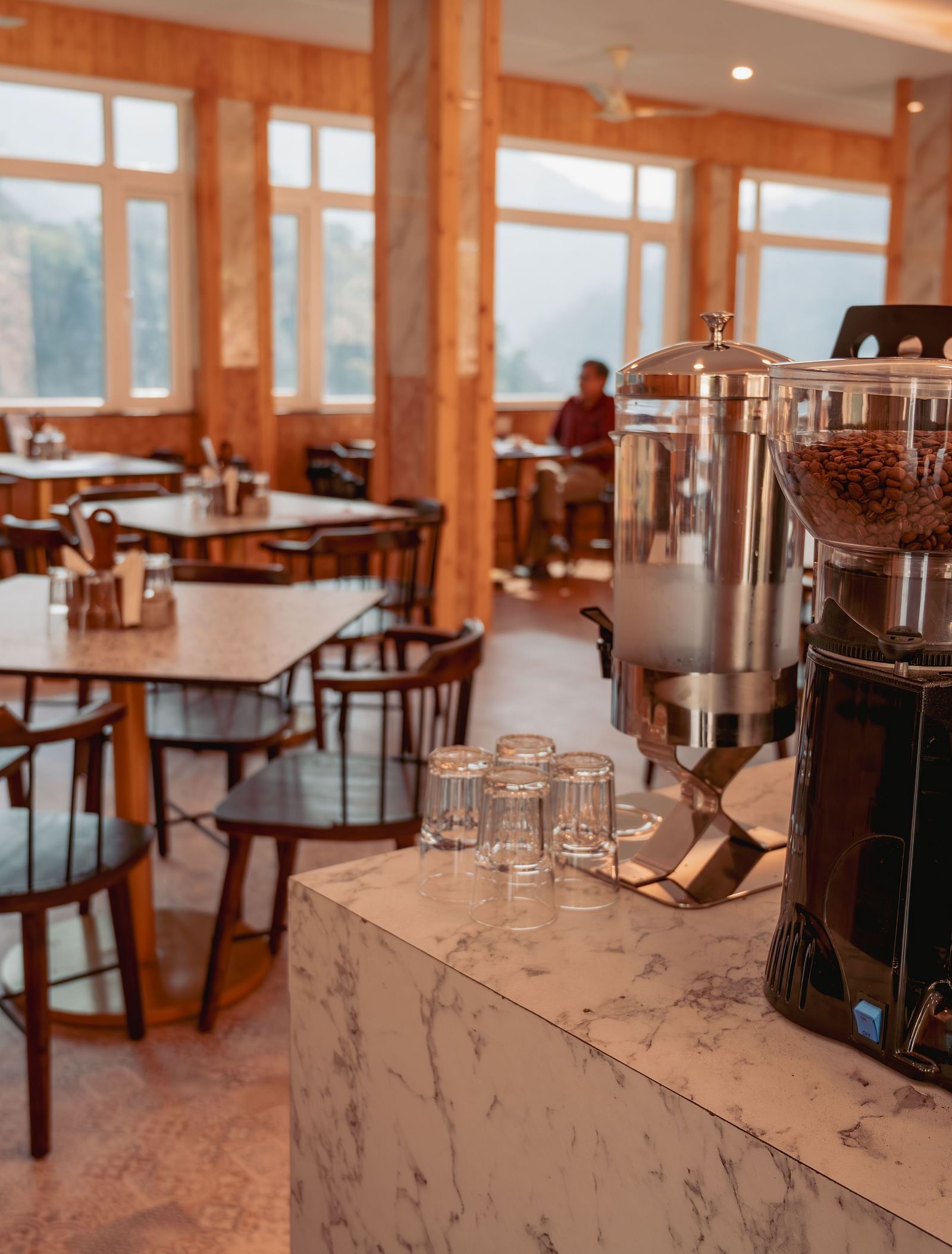Image of the in-house restaurant featuring a fine dining setup, natural lights and a coffee machine | The Tattva Devprayag