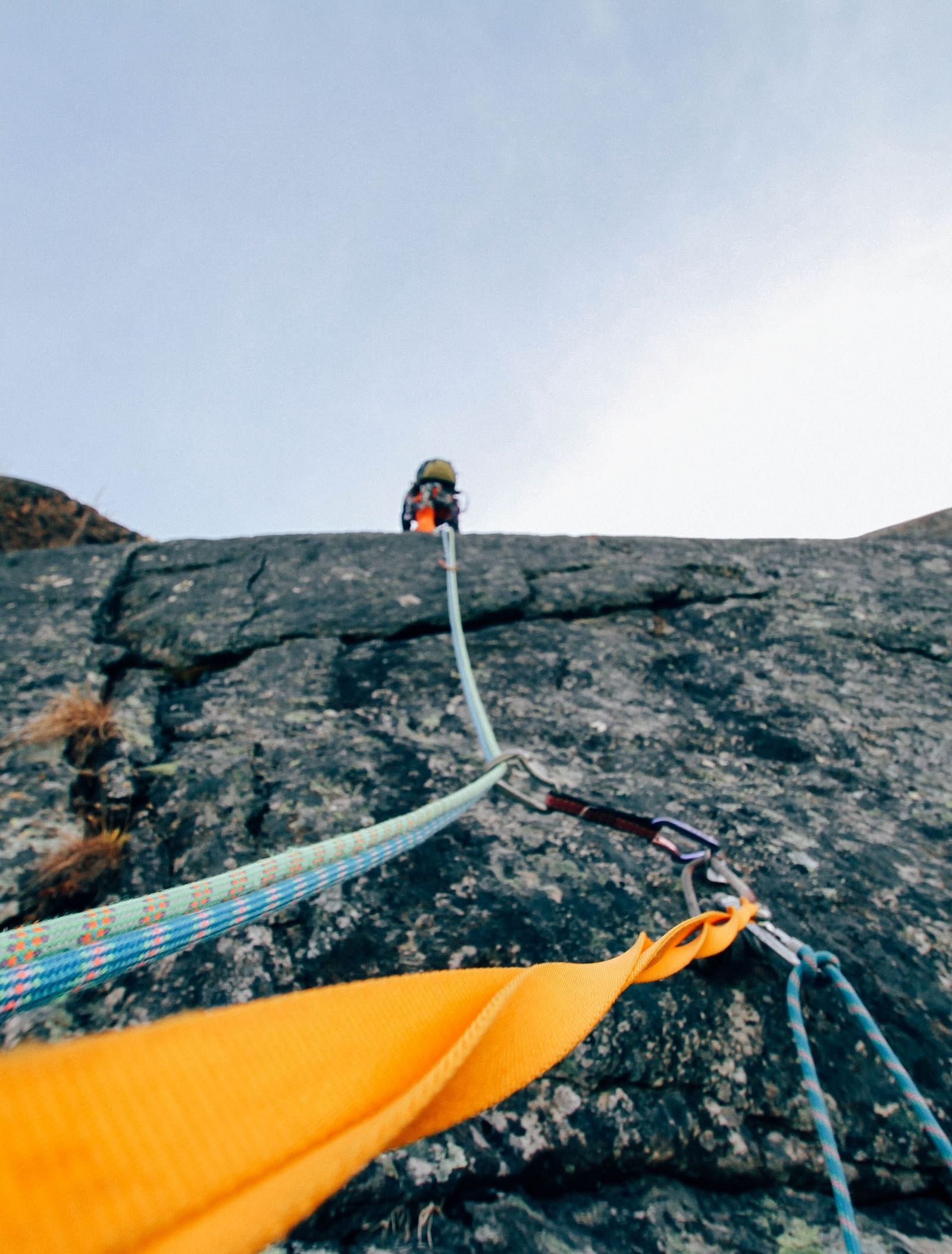 image of a person climbing a mountain cliff holding on to climbing ropes 