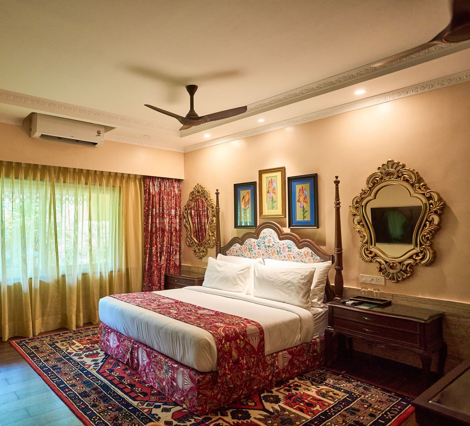 A spacious room featuring a large bed, wooden bedside tables, and windows draped with curtains at Mayfair Manor, Alibag