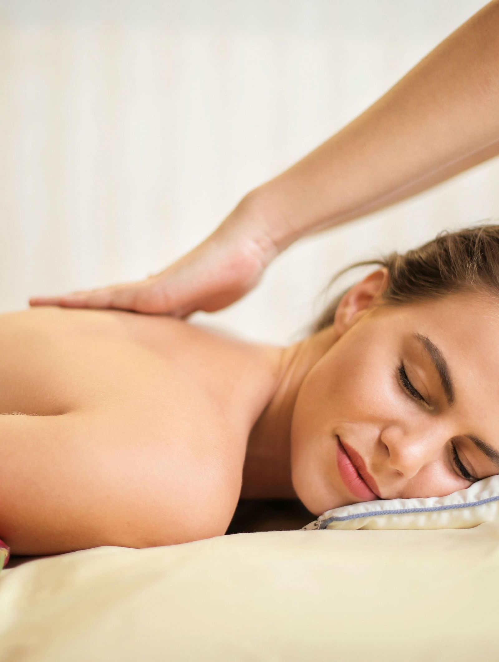 A person receives a back massage, with the masseuse's hand on their back.